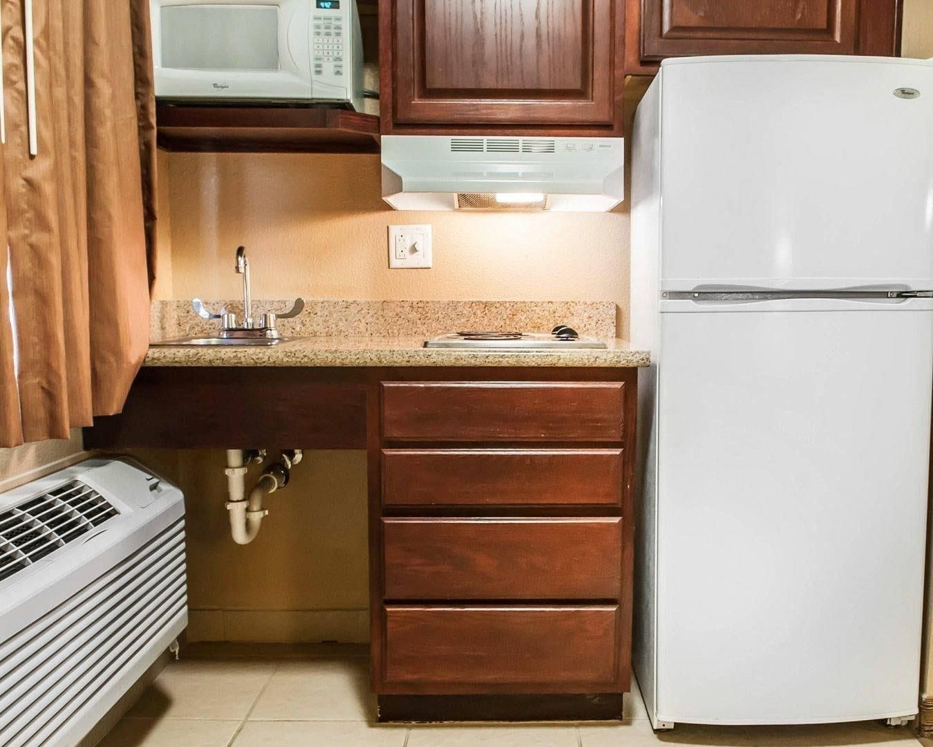 Une cuisine équipée d’un four à micro-ondes, d’une cuisinière, d’un évier et d’un réfrigérateur blanc.