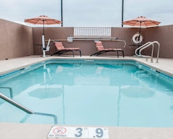 Una piscina interior con una profundidad de 3,9 pies, dos sillas de descanso y dos sombrillas.