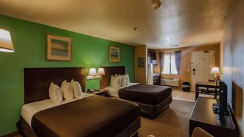 A hotel room with two beds, a desk, and a chair.