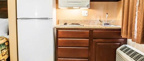 A kitchen with a white refrigerator, wooden cabinets, a microwave, and a built-in oven.