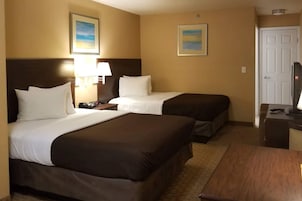 Habitación de hotel con dos camas, un escritorio, un televisor y dos lámparas de pared.