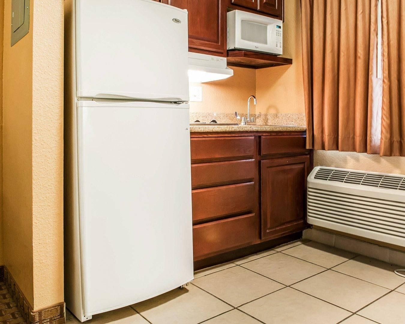 A kitchen with a white refrigerator, wooden cabinets, a microwave, and a built-in oven.