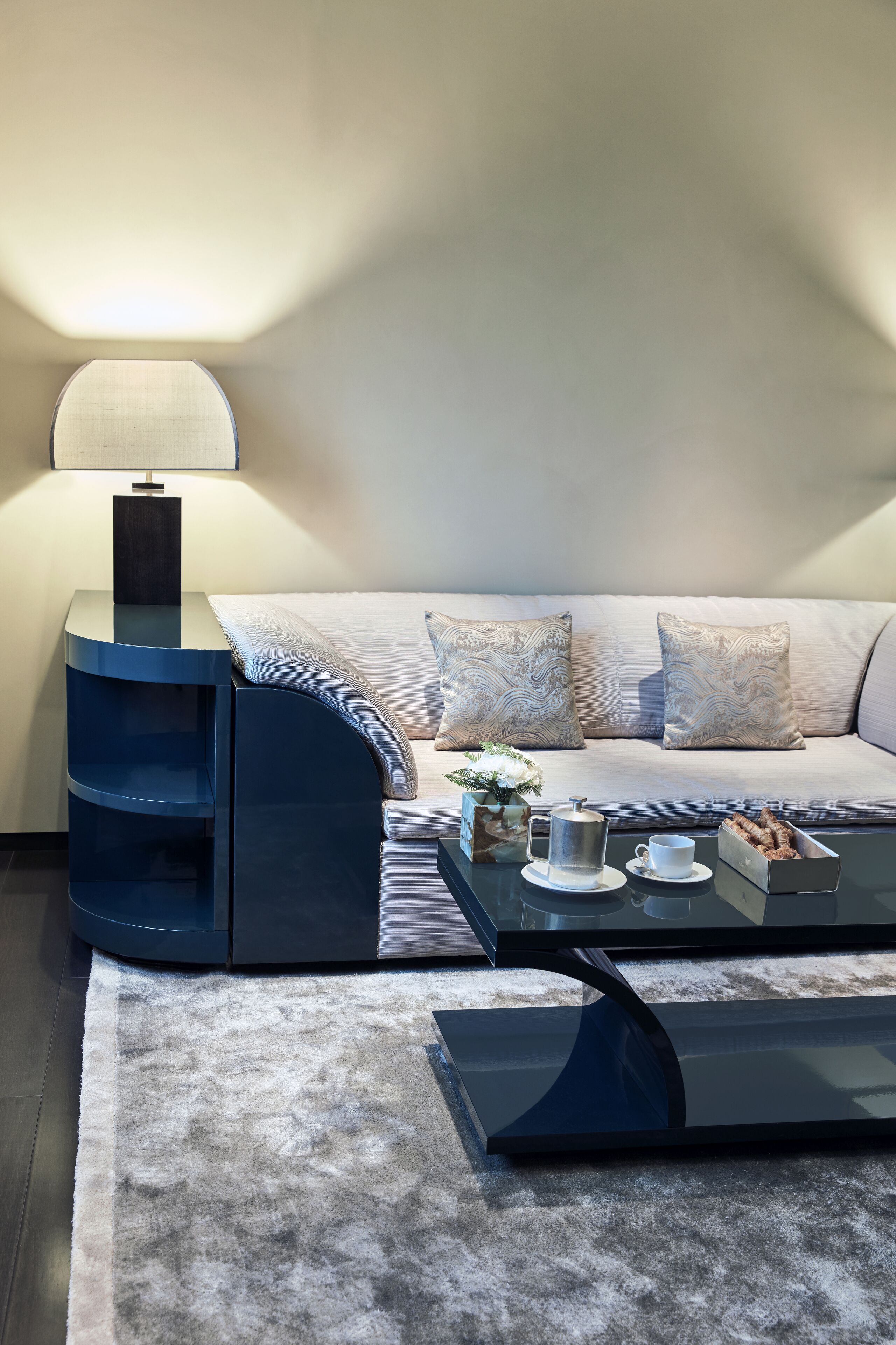 Ein modernes Wohnzimmer mit einer Couch, einem Couchtisch, einer Lampe und einer Vase mit Blumen.