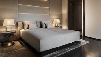 A modern bedroom with a large bed, two bedside tables with lamps, and a dark floor.