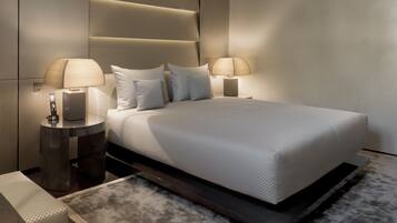 A modern bedroom with a large bed, two bedside tables with lamps, and a built-in headboard.
