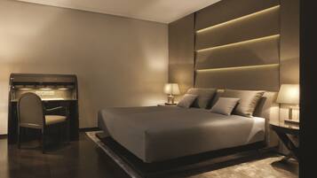 A modern bedroom with a large bed, bedside lamps, a desk, and a chair.