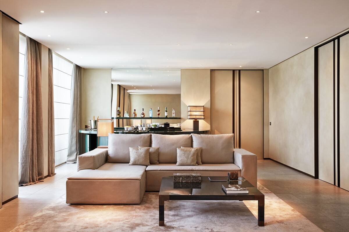 A modern living room with a sectional sofa, a coffee table, and a kitchen area in the background.