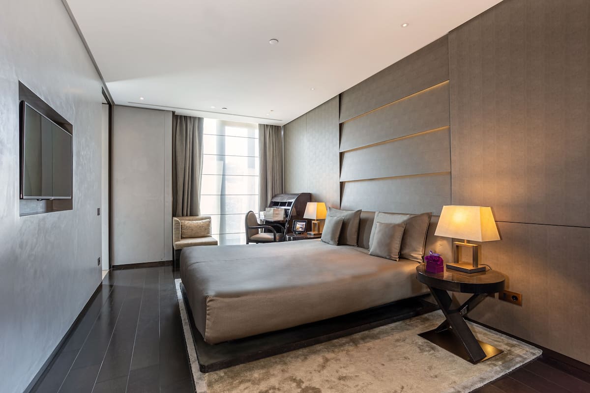 A modern hotel room with a large bed, a desk, and a TV.