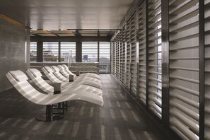 A modern waiting area with reclining chairs and a large window providing a view of the cityscape.