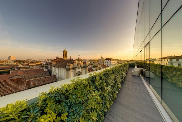 A rooftop terrace with a view of historic buildings and a modern glass building.