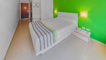 Una habitación de hotel moderna con una cama grande, una mesita de noche y una pared verde de acento.