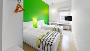 A hotel room with two beds, a green accent wall, a TV, and a window with a view. - City Express Junior by Marriott Veracruz Aeropuerto (Veracruz)