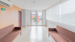 A waiting area with two benches, a door leading outside, and a view of the street through glass doors. - City Express Junior by Marriott Veracruz Aeropuerto (Veracruz)
