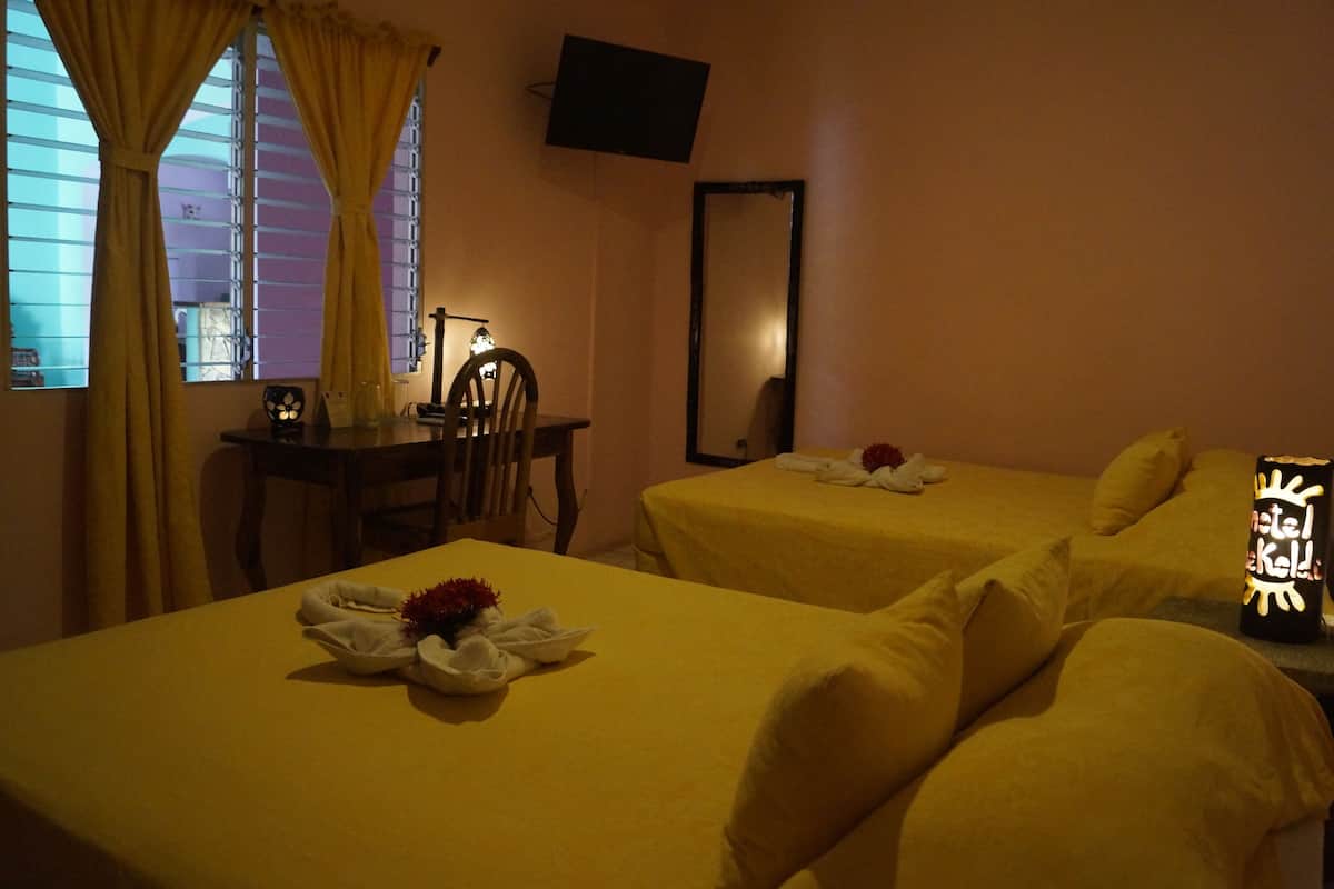 Une chambre d’hôtel avec deux lits, un bureau, une chaise, une télévision et un miroir.