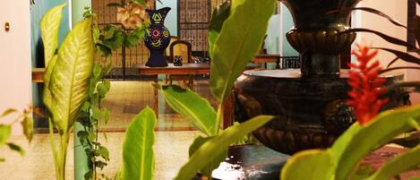 A room with a fountain, potted plants, and a traditional vase.
