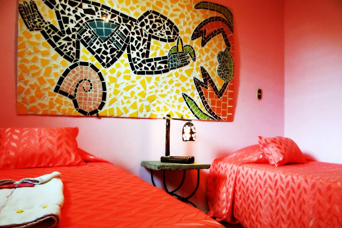Une chambre d’hôtel avec deux lits, une œuvre d’art murale, une table de chevet et une lampe.