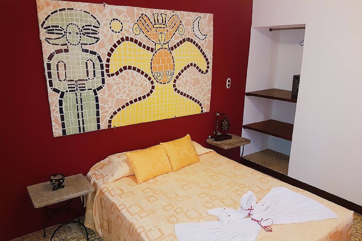 Une chambre d’hôtel avec un lit, une table de chevet, une petite table et une œuvre d’art murale.