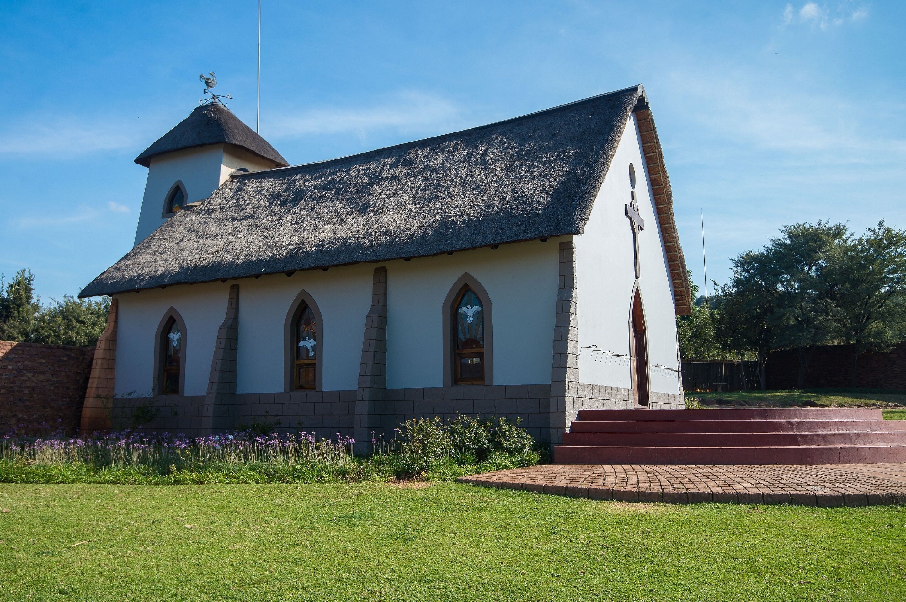 A church with a steeple, arched windows, and a brick facade.