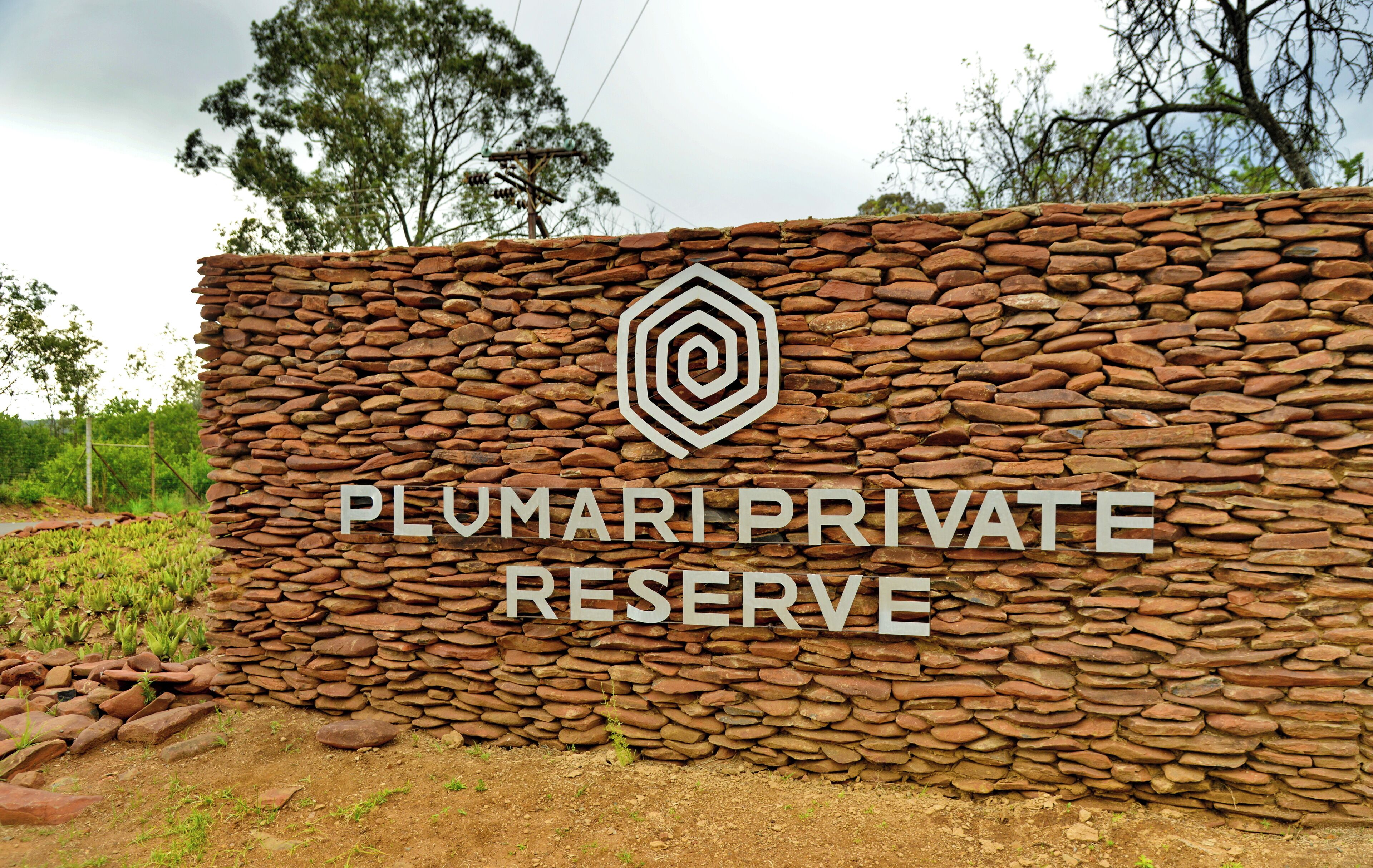 Un muro de piedra con el texto "PLUMARIPRIVATE RESERVE" y un logotipo.