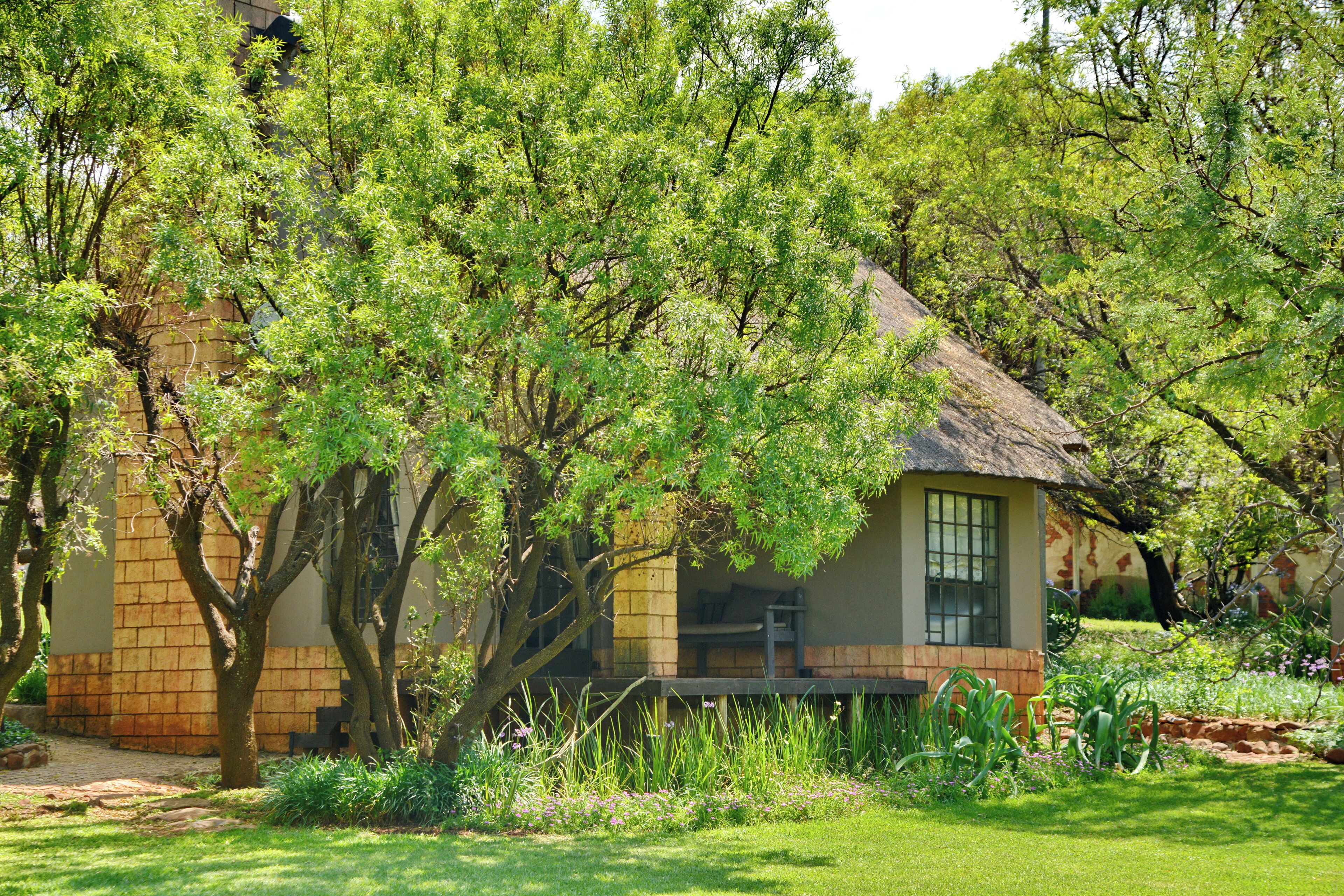 A house with a brick exterior, a thatched roof, and a small porch.