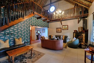 Amplia sala de estar con escalera de madera, chimenea, sofá, banca y pared con diseño.
