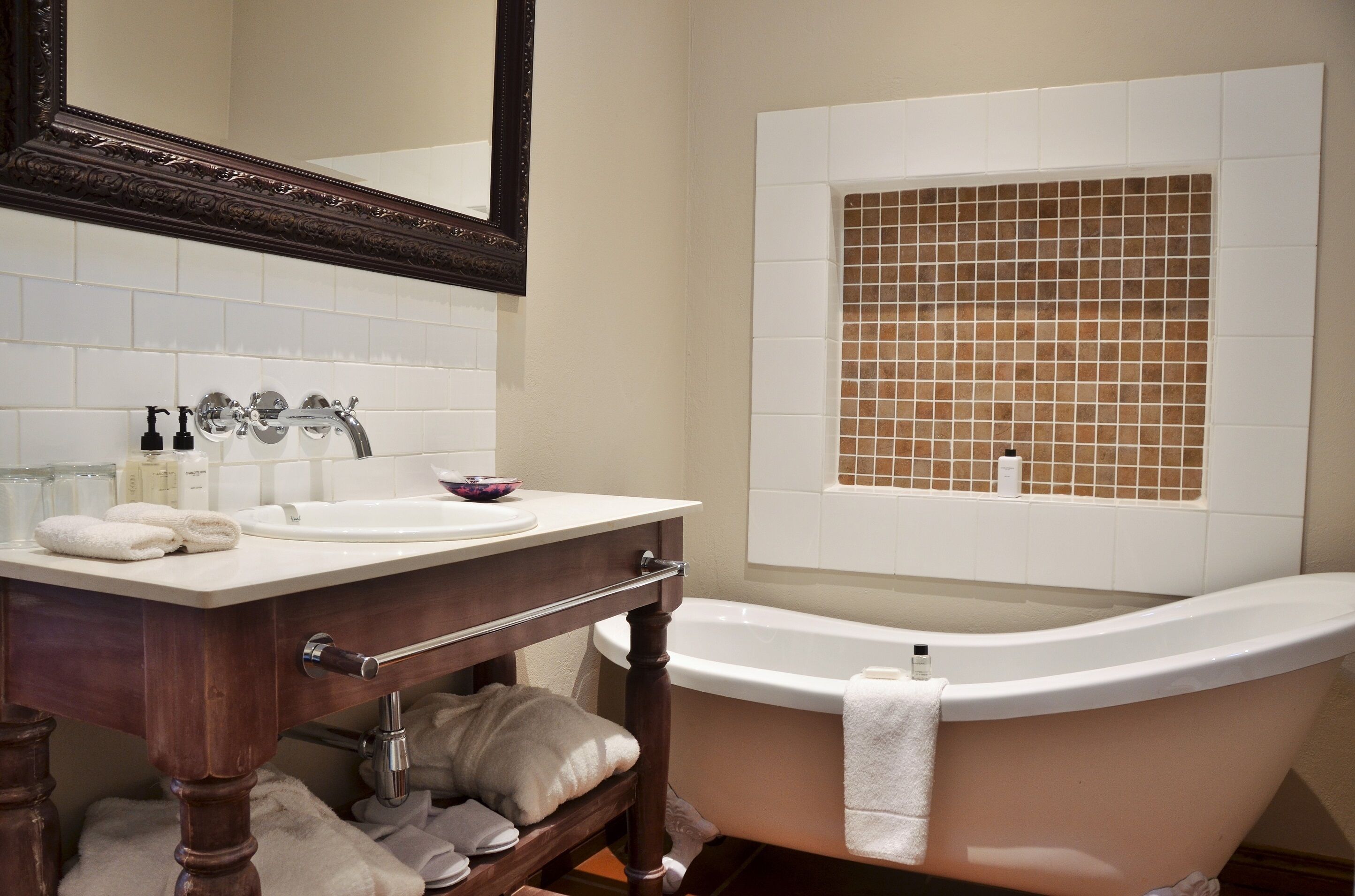 A bathroom with a white bathtub, a large mirror, and a tiled shower area.