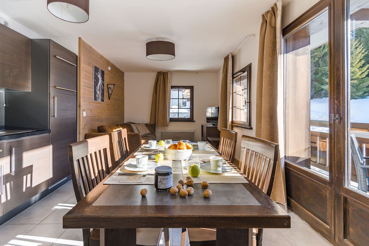 Una cocina moderna con armarios de madera, una mesa de comedor dispuesta para el desayuno y vistas al exterior.