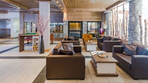 Eine moderne Lobby mit Ledersofas, einer Steinsäule und einem Kamin.