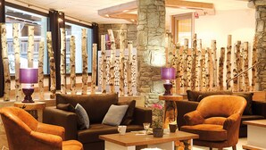 Eine Lobby mit einem braunen Ledersofa, zwei braunen Sessel, einem Couchtisch und einer Steinsäule.