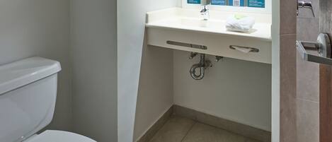 A small bathroom with a white toilet, a sink with a mirror, and a towel on the sink.