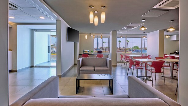 Un área de comedor moderna con sofá, mesas y sillas.