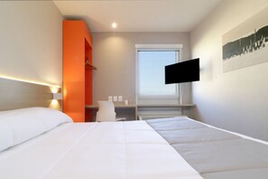 A hotel room with a bed, a desk, a chair, a TV, and a window. - City Express Junior by Marriott Tijuana Otay (Tijuana)