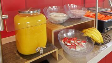 A buffet setup with a fruit punch dispenser, bowls of cream cheese, and a basket of bananas.