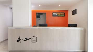A reception desk with a sign reading "cityexpress junior" and a symbol indicating a check-in area.