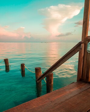 A wooden deck with a railing overlooking turquoise water. - Splash Inn Dive Resort & Villas (Roatan)