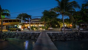 A waterfront property with a wooden dock leading to a building with a covered patio area.