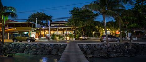 A waterfront property with a wooden dock leading to a building with a covered patio area.