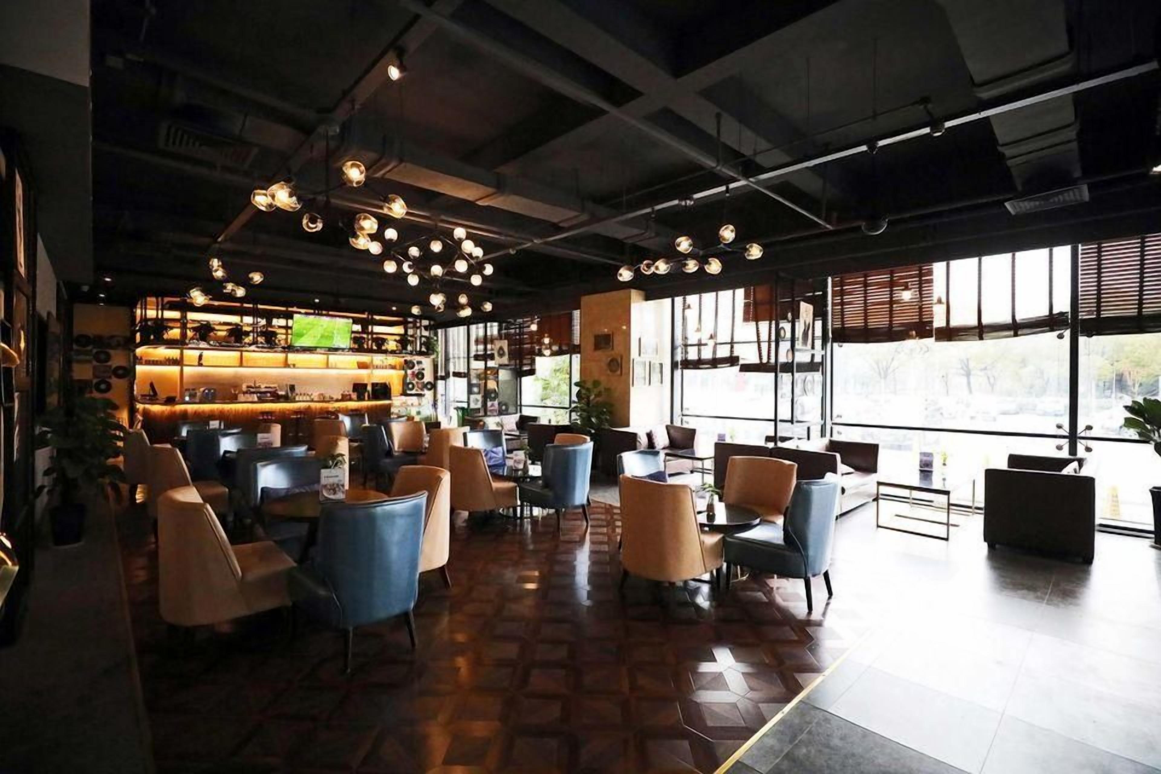 Um interior moderno com área de bar, assentos e amplas janelas.