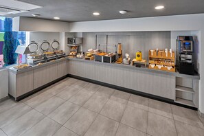 Un bar à petit-déjeuner moderne, doté de stations en libre-service, comprenant des machines à café et une variété d’options alimentaires.