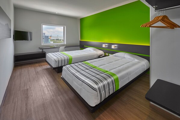 Una habitación de hotel moderna con dos camas, un escritorio y un televisor.