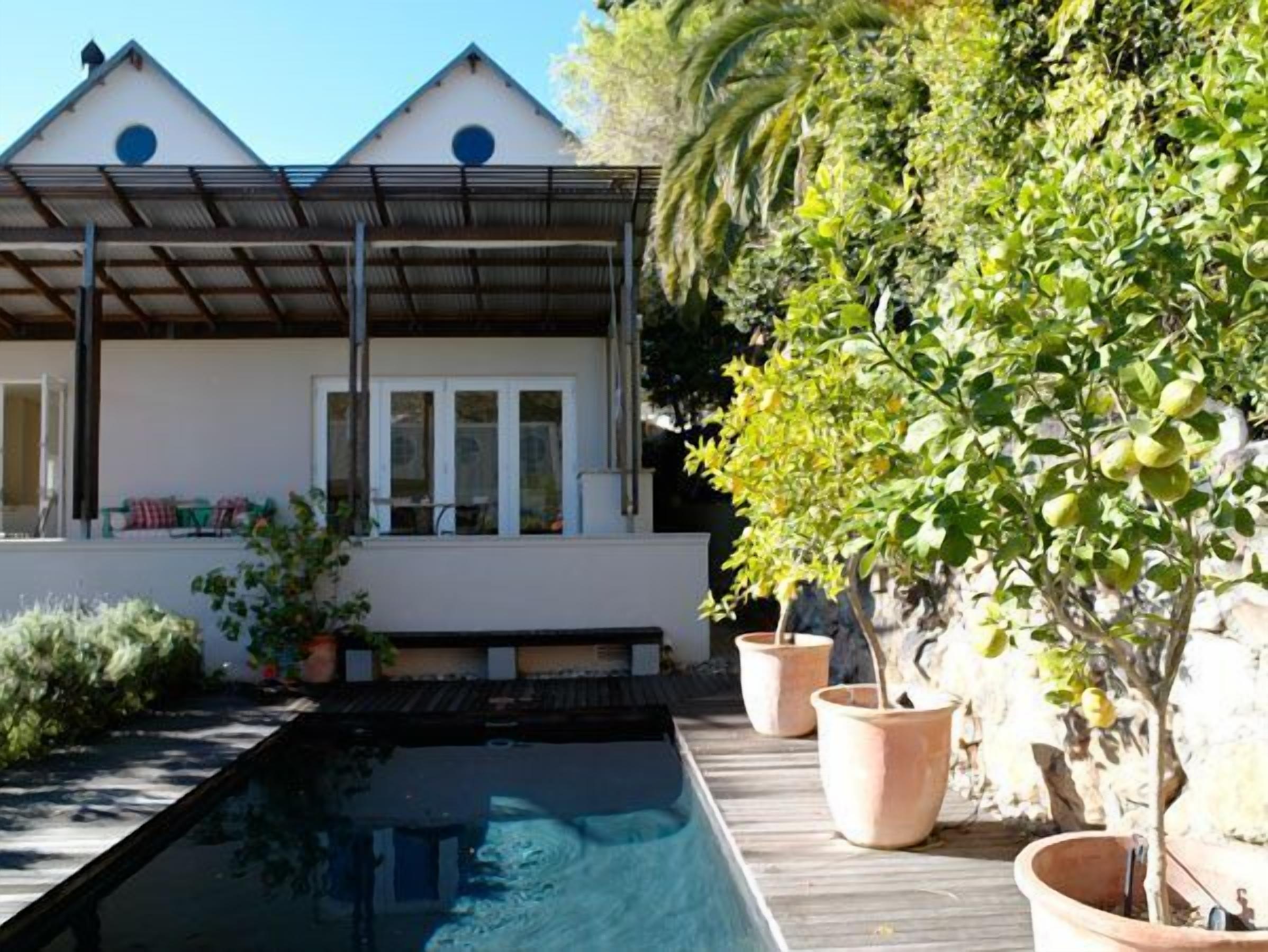 A house with a pool, potted plants, and a wooden deck.