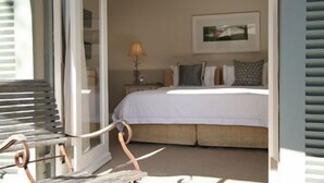 A bedroom with a bed, pillows, a nightstand, and a lamp. - Four Rosmead (Cape Town)