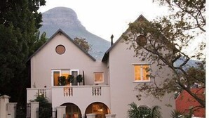 A two-story building with a symmetrical facade, arched windows, and a balcony. - Four Rosmead (Cape Town)