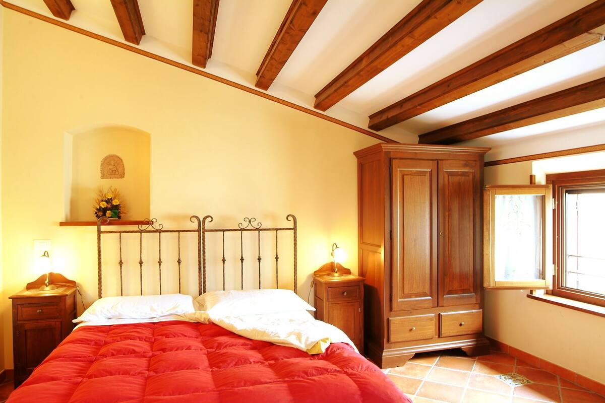 A bedroom with a bed, wooden wardrobe, and a window.