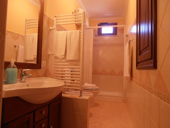 A bathroom with a sink, mirror, towel rack, and shower area. - Il Castello (Petralia Sottana)