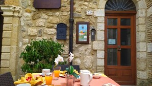 Un desayuno con platos de comida, una cafetera y una mesa frente a un edificio de piedra con un letrero que dice "Castello".