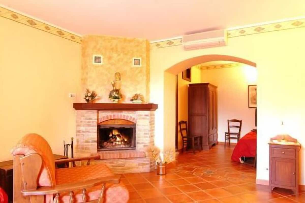 A cozy living room with a fireplace, wooden furniture, and a tiled floor.