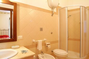 A bathroom with a sink, toilet, bidet, and a glass-enclosed shower. - Il Castello (Petralia Sottana)