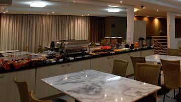 A buffet area with marble-topped tables and wicker chairs, featuring a variety of food items and a buffet station.