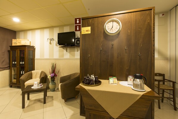 A hotel room with a wooden reception desk, a clock, a television on the wall, and a cabinet with glass doors. - Hotel La Piana (Tito)